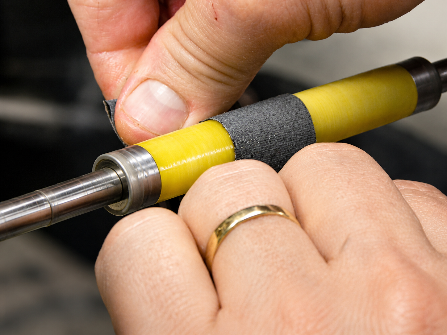 Close-up of hands shaping a Pen Part resin component with a precision tool in the workshop